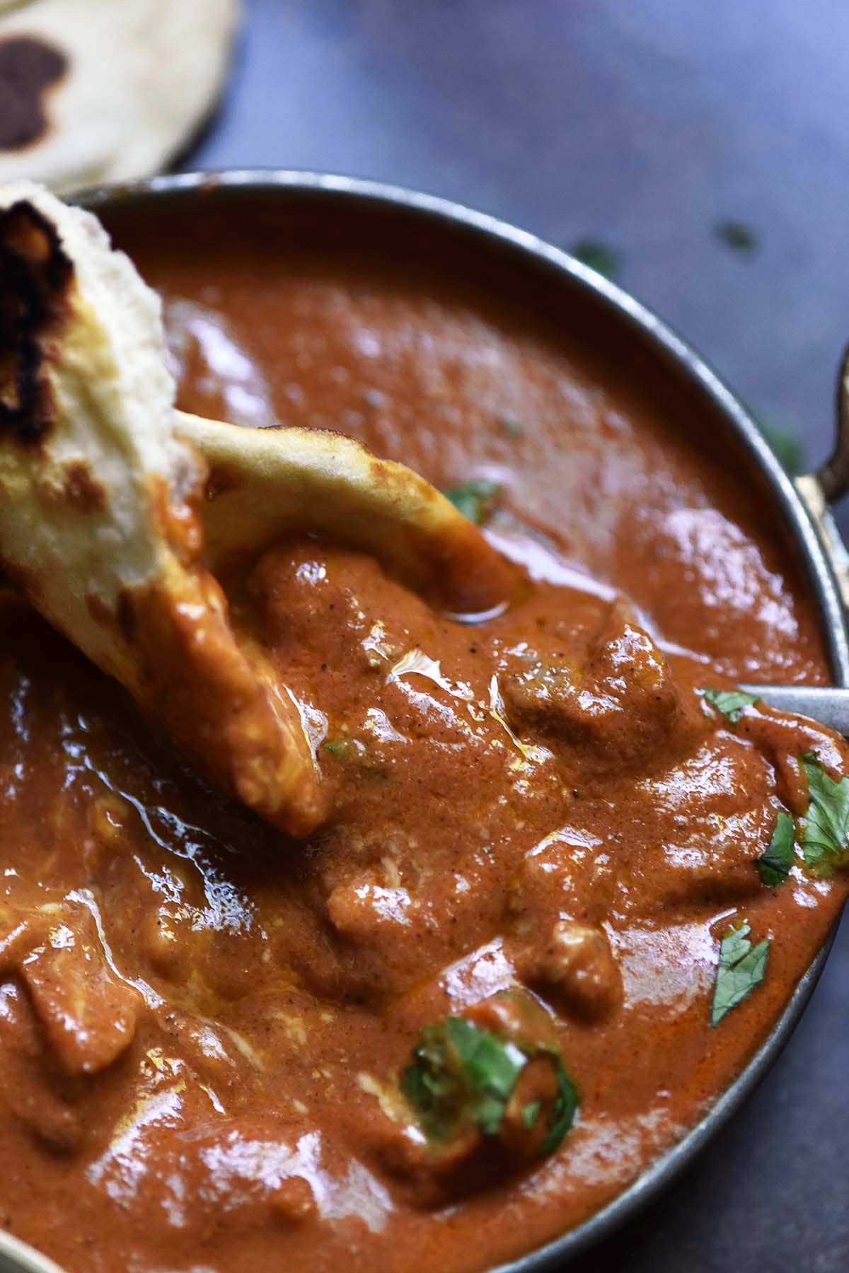 dipping sourdough naan into restaurant style indian butter chicken gravy