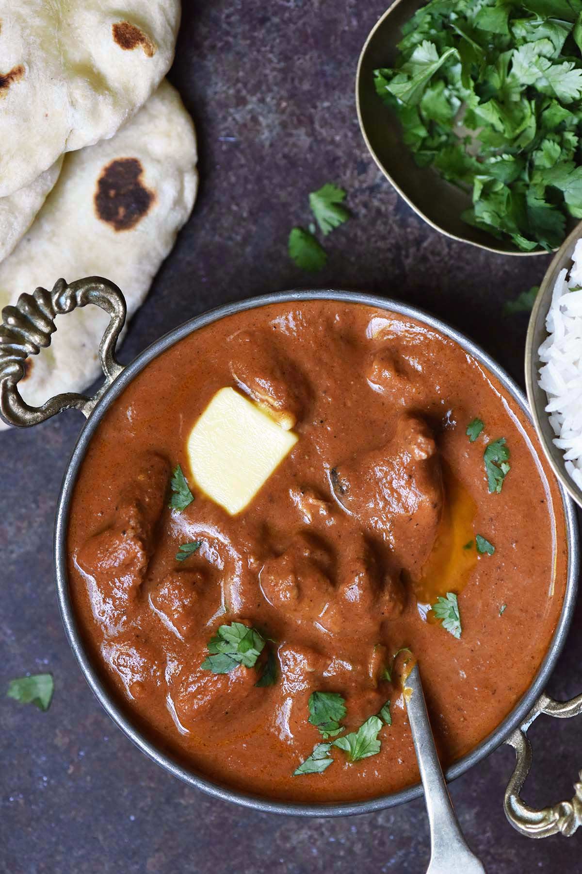 top view of butter chicken with gravy in authentic indian dish next to naan bread