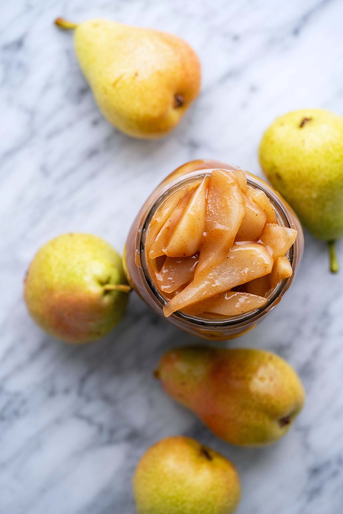top view of glass jar with homemade pear pie filling on marble countertop