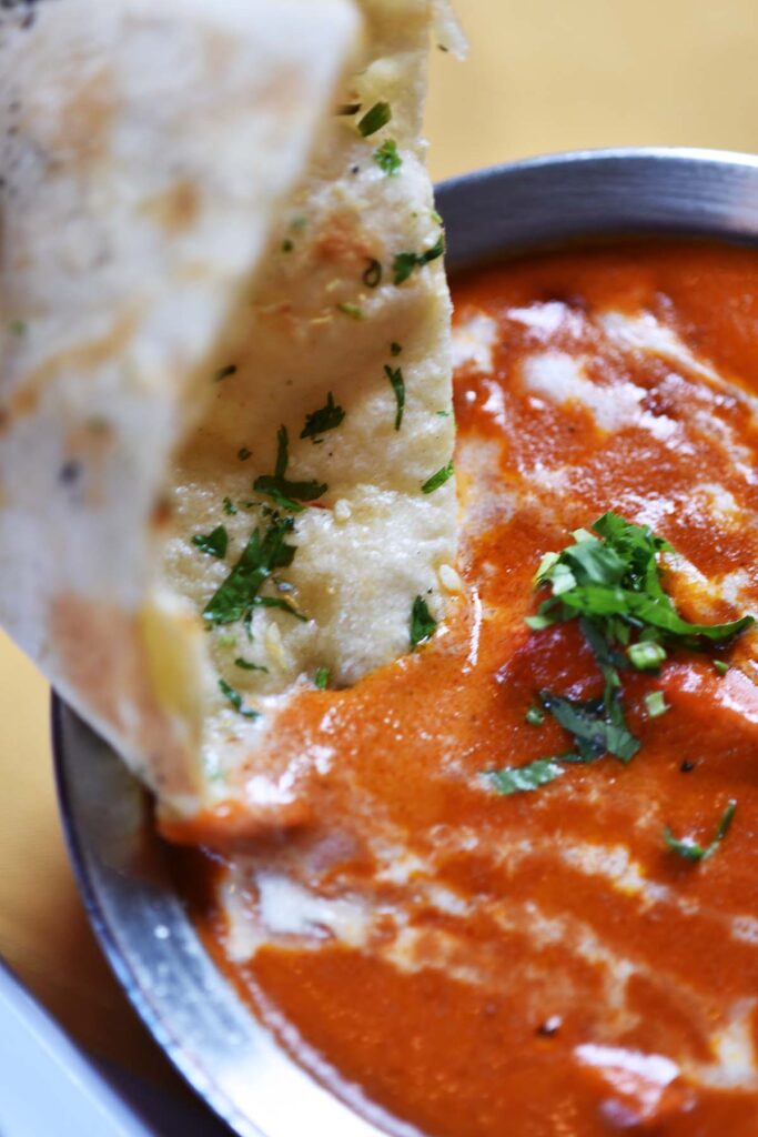 dipping garlic naan into butter chicken sauce at DIYA