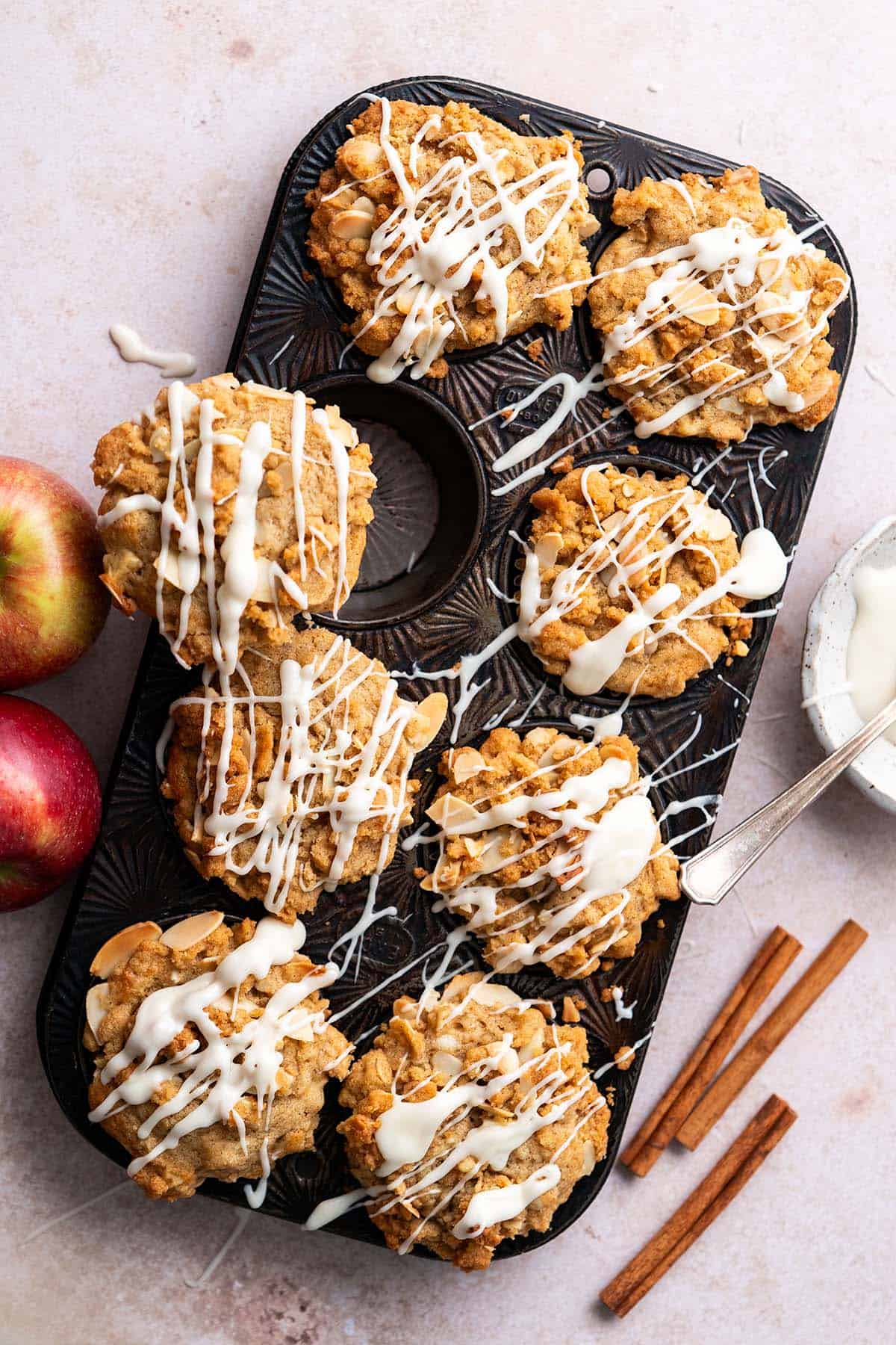Apple muffins with crumble topping and vanilla icing in vintage ovenex tray.
