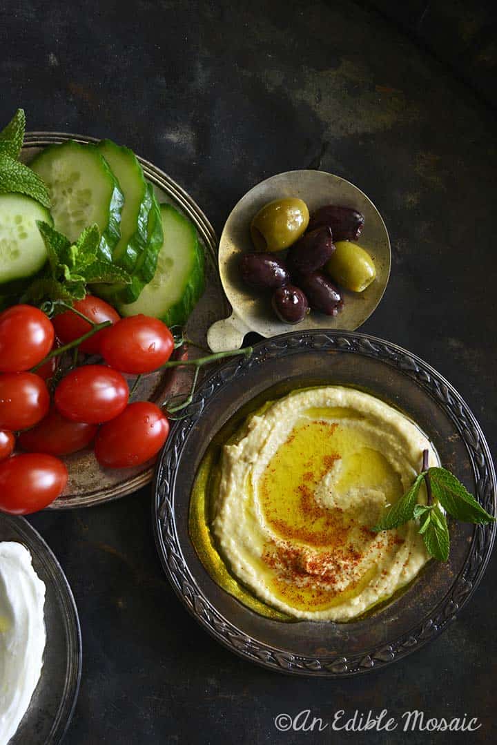 Hummus på mørk bakke med oliven og cherrytomater